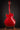 Red guitar on a stand against a dark background