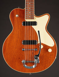 Brown electric guitar with a white pickguard on a dark background