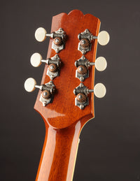 Close-up of a guitar headstock with tuning pegs on a dark background