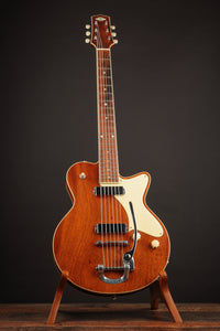 Wooden electric guitar on a stand against a dark background