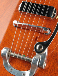 Close-up of a guitar's bridge and tailpiece on a wooden body.