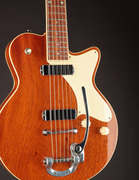 Close-up of a wooden electric guitar with a dark background