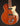 Brown electric guitar with a white pickguard on a dark background