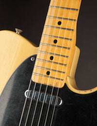 Close-up of neck and pickup on a Blonde 1953 Fender Telecaster against a dark background