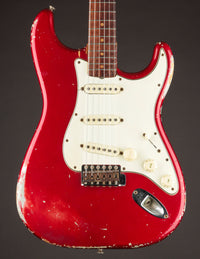 1964 candy apple red Fender Stratocaster electric guitar with a worn finish on a dark background