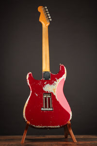 1964 candy apple red Fender Stratocaster  electric guitar on a stand against a dark background, back view