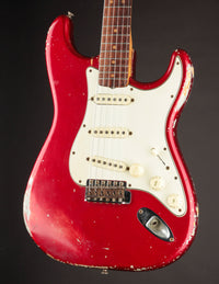 1964 candy apple red Fender Stratocaster electric guitar with a white pickguard on a dark background