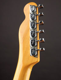 Close-up of a guitar headstock with tuning pegs on a dark background