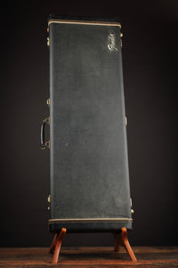 Vintage Fender guitar case on a stand against a dark background