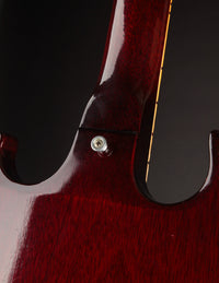 Close-up of a red electric guitar's body with a dark background