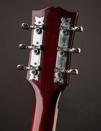 Close-up of a guitar headstock with tuning pegs on a dark background