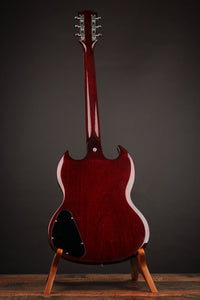 Red electric guitar on a stand against a dark background