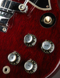 Close-up of a red electric guitar with control knobs on a dark background