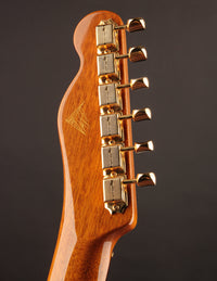 Close-up of a guitar headstock with gold tuning pegs on a dark background