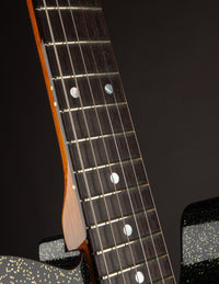 Close-up of a guitar neck with frets and strings on a dark background