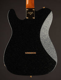 Back view of a black electric guitar with a Fender logo on a dark background