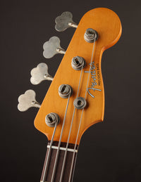 Fender Precision Bass headstock with tuning pegs on a dark background