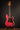Red electric bass guitar on a stand against a dark background