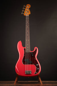 Red electric bass guitar on a stand against a dark background