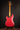 Red electric guitar on a stand against a dark background