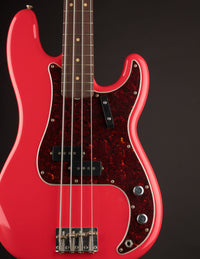 Red electric bass guitar with a red body on a black background