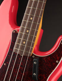 Close-up of a red electric bass guitar's neck joint with a dark background
