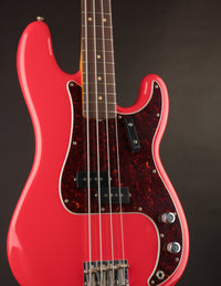 Red electric bass guitar with a dark brown tortoiseshell pickguard on a black background