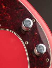 Close-up of a red electric guitar with control knobs on a dark background
