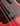 Close-up of a red electric bass guitar's pickup with tortoiseshell pickguard