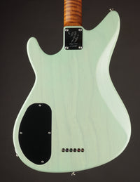 Guitar with a light green finish and wooden neck on a dark background