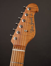 Close-up of a guitar headstock with 'Don Grosh' branding on a dark background