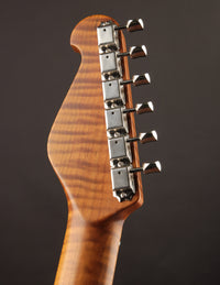 Close-up of a guitar headstock with tuning pegs on a dark background