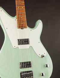 Green electric guitar with a brown pickguard on a dark background