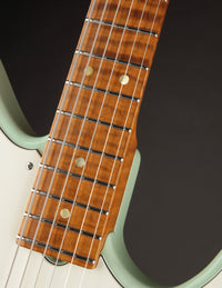 Close-up of a guitar neck with frets and strings against a dark background
