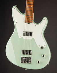 Green electric guitar with a white pickguard on a dark background