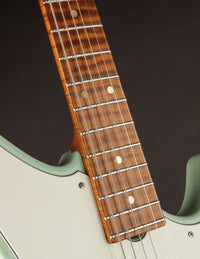 Close-up of a guitar neck with a dark brown fretboard and white pickguard.