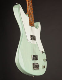 Green electric baritone guitar with a brown neck on a black background