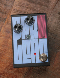 Effect pedal with control knobs and a footswitch on a wooden surface