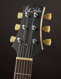 Guitar headstock with 'Nik Huber' branding on a dark background