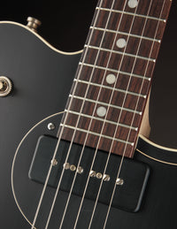 Close-up of a guitar's neck and neck P90 pickup with a black body.