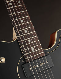 Close-up of a guitar neck with fretboard on a dark background
