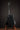Black electric guitar on a stand against a dark background