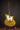 Gold electric guitar on a stand against a dark background