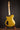 Gold electric guitar on a stand against a dark background