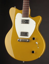 Gold electric guitar with a white pickguard on a black background