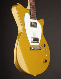 Gold electric guitar with a white pickguard on a dark background, side view
