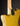Close-up of a gold electric guitar with a visible brand logo on a dark background