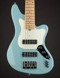 Turquoise electric bass guitar with a white pickguard on a black background