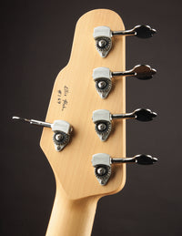 Close-up of a guitar headstock with tuning pegs on a dark background