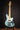 Blue electric bass guitar on a stand against a dark background